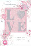 This anniversary card looks like it was designed for a couple who enjoy the softer side of celebration in Hoddesdon, favouring gentle beauty over grand gestures. The surface is suffused with the tender tones of blush pink, creamy white, and subdued silver, creating an atmosphere of calm romance. At the centre, the word LOVE stands out in embossed, raised letters, their edges traced with fine glitter that glistens when it catches the light, much like sunlight on petals in a Hoddesdon garden. The tactile nature of the lettering is evident, suggesting a pleasant contrast between the smooth card and the slightly roughened sparkle. Surrounding this central word, delicate floral motifs and looping leaves meander gracefully across the card. The flowers are stylised and elegant, their petals outlined in slender lines and shaded with soft pinks and pearly whites, while occasional hints of silver add a sophisticated sheen. These botanical shapes swirl gently around the text, framing it in loose, airy clusters that echo the natural flow of a hand-tied bouquet. The background remains a consistent blush tone, allowing the white and silver details to stand out with quiet clarity. Inside, flowing script conveys heartfelt anniversary sentiments, the typography mirroring the curves and flourishes of the floral artwork outside. Together, the colours, textures, and illustrations form a design that feels personal and enduring-a card you might pair with a bouquet from a favourite Hoddesdon florist to mark another year of shared life, laughter, and the kind of love that grows patiently over time.